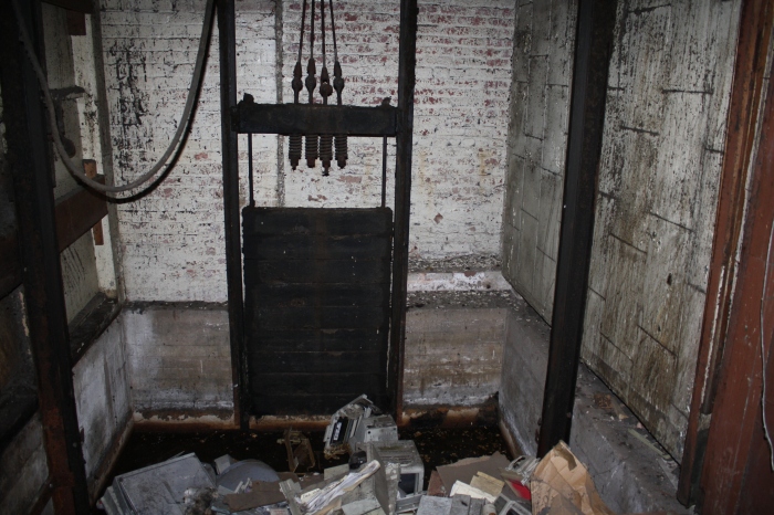 Open elevator shaft and elevator floor on the first floor of the building.